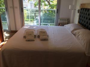 a white bed with two towels on it with a window at Apart Edificio Clever in La Plata +22 photos