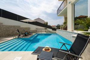 a swimming pool with two chairs next to a house at Hotel - Aparthotel Teranea in Hvar