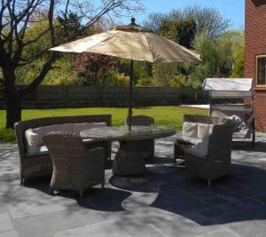 un patio con mesa, sillas y sombrilla en Orchid House en Southport