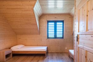 um quarto com uma cama num chalé de madeira com uma janela em Atlanta Domki i Apartamenty em Ustronie Morskie