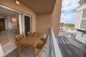 a balcony with a wooden table and chairs and a street at La Farmacia in Gran Tarajal