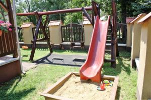 a playground with a slide in the grass at Harmónia Apartmanház in Hajdúszoboszló