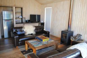 a living room with a leather couch and a stove at Casa Negra Nevados de Chillan in Las Trancas