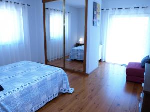 een slaapkamer met een wit bed en een spiegel bij Casa Escusa in Caminha