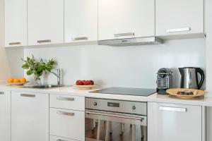 una cocina blanca con armarios blancos y fregadero en Glasir Apartments Barcelona, en Barcelona