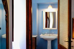 een blauwe badkamer met een wastafel en een spiegel bij Sofia Family Suites in Carloforte