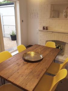 a wooden dining table with yellow chairs around it at Sea Song Cottage in Broadstairs