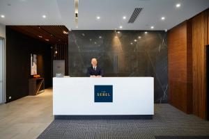 a man standing behind a counter in a lobby at The Sebel West Perth in Perth