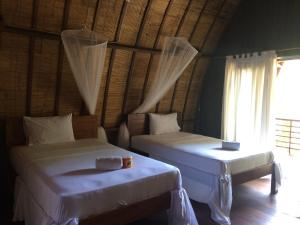 a bedroom with two beds and a window at Melati Cottage in Gili Trawangan