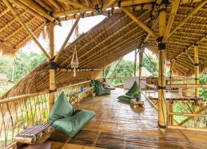 a large straw hut with green pillows on a wooden floor at Bamboo & B in Licin