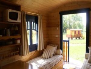 a living room with a couch and a large window at Les Roulottes & Cottages du Moulin in Chenillé-Changé