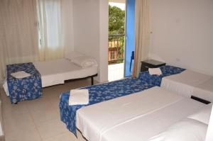 a room with three beds and a window at Hotel Bahía Cadi in Puerto López