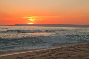 a sunset on the beach with the ocean at Zahara Sol Villas y Apartamentos by QHotels in Zahara de los Atunes