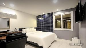 a bedroom with a white bed and a black wall at Hotel Louis in Busan