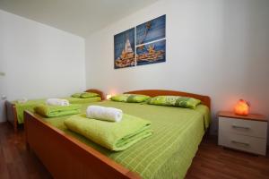 two beds in a room with green sheets and towels at Apartments Barbati in Kustići +99 photos