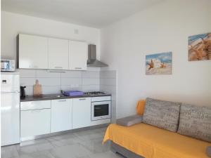 a kitchen with white cabinets and a couch in a room at Apartments Barbati in Kustići