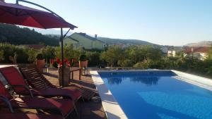 a swimming pool with chairs and an umbrella at Villa Rosana in Rab