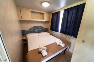 a small room with a bed and two towels at Villaggio Diomedea in Campomarino +59 photos
