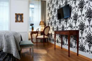 a bedroom with a desk and a tv on a wall at Townhouse Boutique Hotel in Zürich