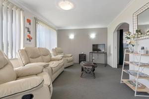 a living room with white couches and a tv at Aruba Apartments in Burnie