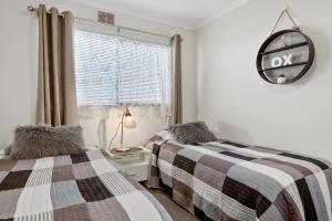 two twin beds in a bedroom with a window at Aruba Apartments in Burnie