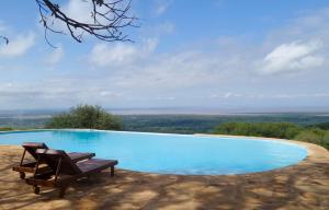 a swimming pool with a chair and a view at Migombani Camp in Mto wa Mbu