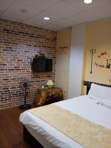 a bedroom with a bed and a brick wall at Pu Shi Homestay in Yuli