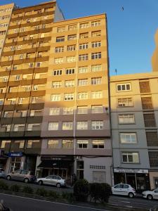 a yellow building with cars parked in front of it at Acogedor apartamento en Ronda Outeiro 210 in A Coruña