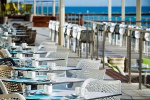 a row of tables and chairs with the ocean in the background at Ammon Zeus Luxury Beach Hotel in Kallithea Halkidikis
