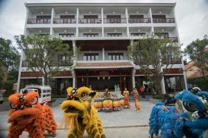 a group of people in dragon costumes in front of a building at Vinh Hung Old Town Hotel in Hoi An