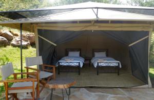 two beds in a tent with a table and chairs at Migombani Camp in Mto wa Mbu