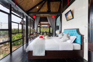 a bedroom with a large white bed with a blue headboard at An Bang Stilt House Villa in Hoi An