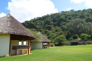 two huts with thatched roofs with a mountain in the background at Migombani Camp in Mto wa Mbu