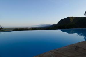 a swimming pool with blue water and mountains in the background at Migombani Camp in Mto wa Mbu