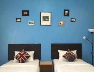 twee bedden in een kamer met een blauwe muur bij Ubon Best Place in Ubon Ratchathani