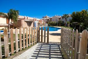 a wooden fence with a gate in front of a pool at Zahara Sol Villas y Apartamentos by QHotels in Zahara de los Atunes
