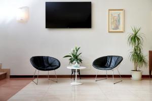 twee zwarte stoelen en een tafel met een tv aan de muur bij Eco Hotel Benacus in Malcesine
