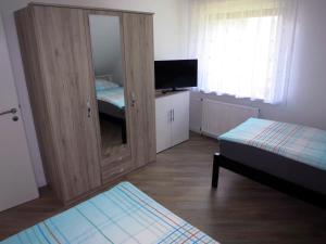 a room with two beds and a cabinet with a mirror at Ferienwohnung Hamburg / Lüneburg in Scharmbeck