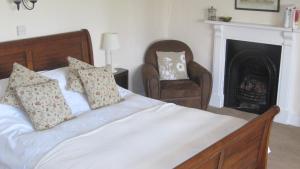 a bedroom with a bed with a chair and a fireplace at Seymours Court in Frome