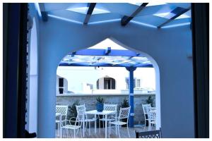eine Terrasse mit weißen Stühlen, einem Tisch und einem Sonnenschirm in der Unterkunft TorreBlu Residence in Torre Lapillo