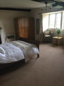 a bedroom with a bed and a chair and window at Seymours Court in Frome