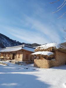 a building with snow on the ground in front of it at Jukheon Traditional House in Andong