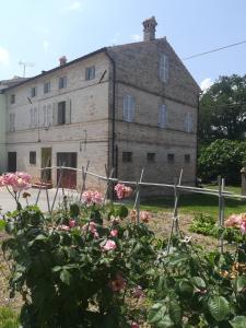 een oud gebouw met roze bloemen ervoor bij Casa Vacanze da Peppa in Grottazzolina