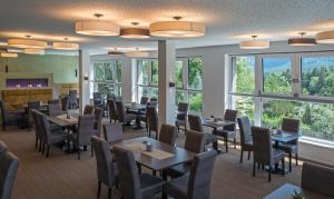 uma sala de jantar com mesas, cadeiras e janelas em Arthur's Hotel und Apartments am Achensee em Maurach