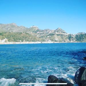 una vista del océano con montañas en el fondo en HOUSE OF GIANNY (The Wolf Nest), en Taormina