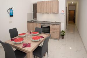 una cocina con una mesa de madera con platos y sillas rojos en For Rest Aparthotel, en St Paul's Bay