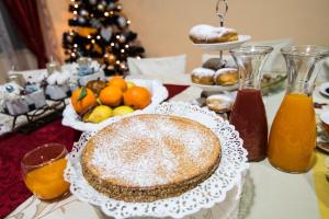 B&B AL VICOLO DI MEZZO في مونزامبانو: طاولة مع كعكة و برتقال و شجرة عيد الميلاد