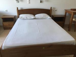 a bed with white sheets and two pillows on it at Eugenia travasarou sea view appartments in Diakofti