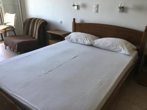 a large white bed with two pillows and a chair at Eugenia travasarou sea view appartments in Diakofti