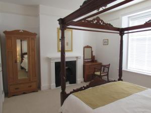 a bedroom with a canopy bed and a fireplace at Kenmuire Apartment in Weymouth